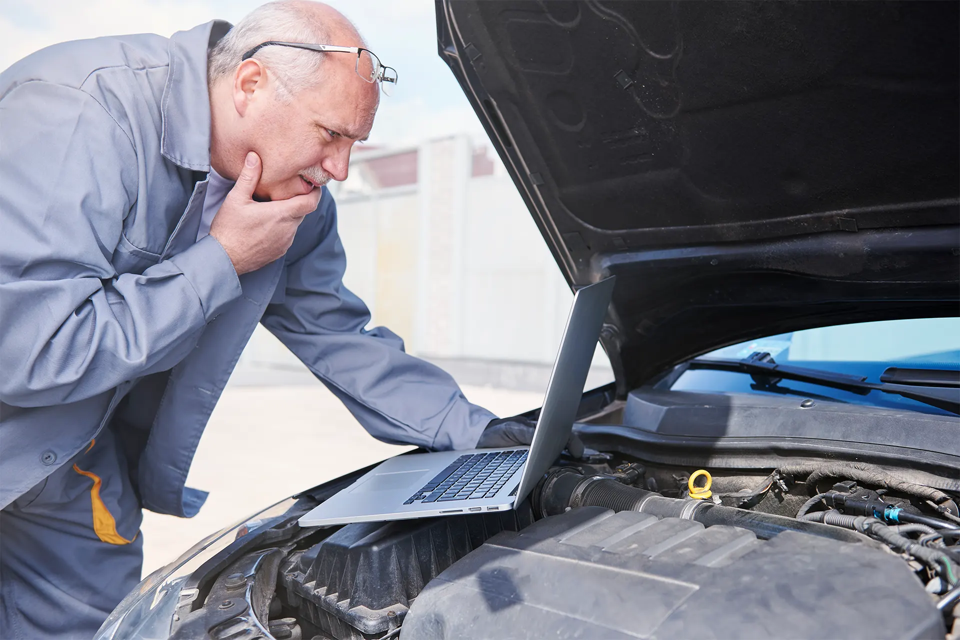 Mechaniker mit Laptop diagnostiziert AdBlue-Fehlercode P20E8 bei TÜV-Prüfung im Motorraum