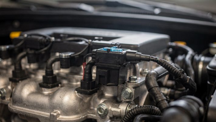 Das Bild zeigt die Zündspule im Motorraum und hilft den Lesern, diese Komponente zu identifizieren.