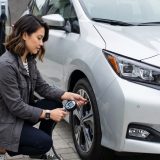 Das Bild vermittelt die emotionale Geschichte von Selbstvertrauen und Verantwortung beim ersten eigenen Auto. Die junge Fahrerin zeigt aktive Aufmerksamkeit, die der Artikel als Grundstein für kluge Autowartung beschreibt.