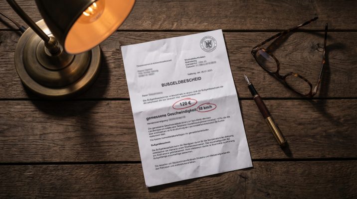 Diese konzeptionelle Still-Life-Aufnahme symbolisiert die juristische und emotionale Schwere des Bußgeldbescheids, die genaues Lesen und Abwägen erfordert, und verleiht dem Thema eine greifbare Alltagsnähe.