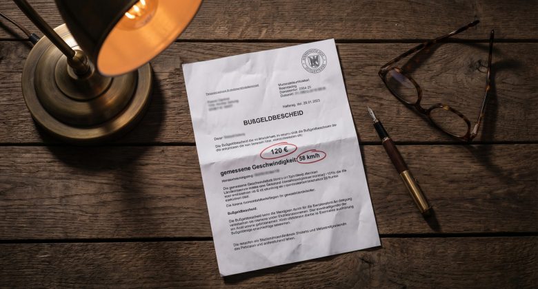 Diese konzeptionelle Still-Life-Aufnahme symbolisiert die juristische und emotionale Schwere des Bußgeldbescheids, die genaues Lesen und Abwägen erfordert, und verleiht dem Thema eine greifbare Alltagsnähe.