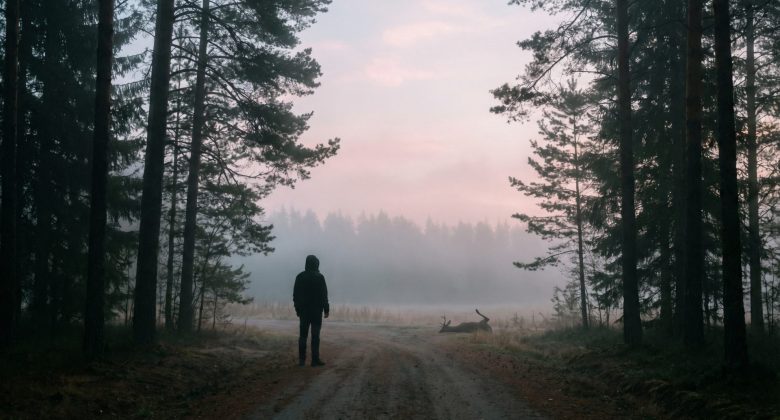 Editorial photograph of a silhouette of a person standing cautiously at the edge