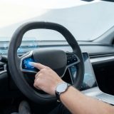 Diese Aufnahme zeigt die intime, konzentrierte Verbindung zwischen Mensch und moderner Fahrzeugtechnologie und vermittelt die vorsichtige Aufmerksamkeit beim Prüfen des Tempomats mit einer emotionalen Nähe zum Fahrer.