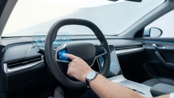 Diese Aufnahme zeigt die intime, konzentrierte Verbindung zwischen Mensch und moderner Fahrzeugtechnologie und vermittelt die vorsichtige Aufmerksamkeit beim Prüfen des Tempomats mit einer emotionalen Nähe zum Fahrer.